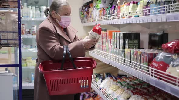 Elderly Woman in Protective Medical Mask and Medicine Gloves Choosing Products in Supermarket