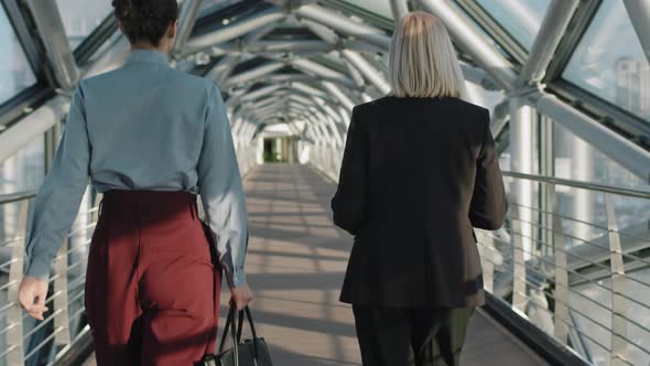 Successful Business Women Walking Along Glass Bridge