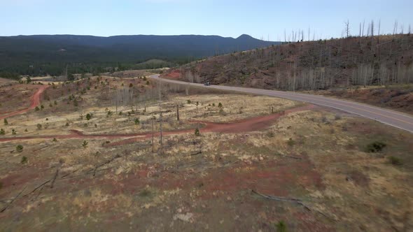 Aerial view following a vehicle on a remote mountain road in the Pike National Forest, Rocky Mountai