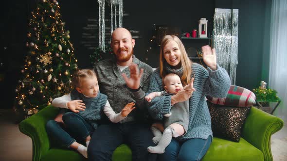 Christmas Concept - Happy Family Sitting on the Couch and Waving Their Hands