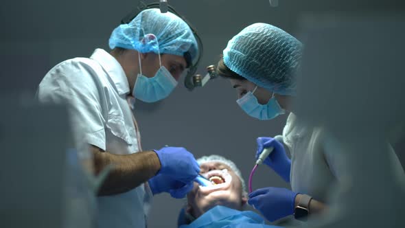 Side View Confident Concentrated Middle Eastern Dentist Injecting Anesthesia Talking to Assistant