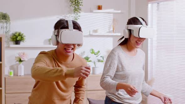 Asian couple playing and enjoying video games with VR head sets at home. Happy couple having fun wit