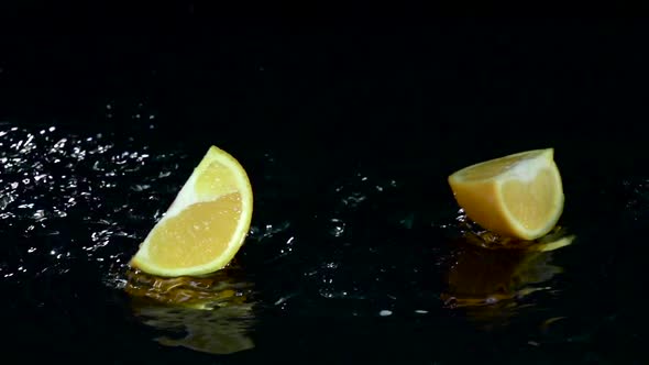 Quarter of Orange Falls Into the Water. Black Background. Slow Motion