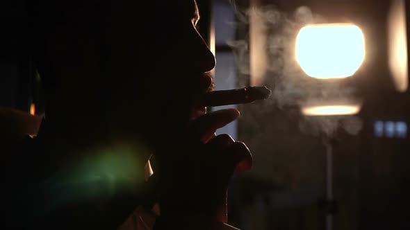 Silhouette Serious Man with a Cigar Who Blows a Lot of Smoke Slow Motion