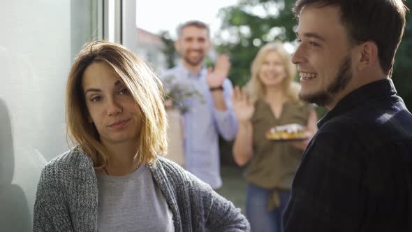 Young Married Couple Meeting Annoying Guests Standing at Doors