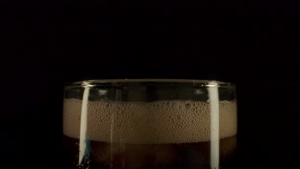 Cola Foam Dissolving in Glass