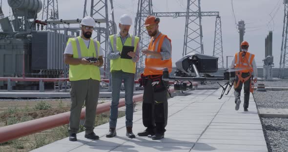 Employees Using Tablet and Controlling Drone on Power Station