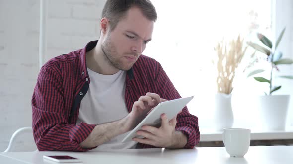 Young Man Browsing and Scrolling on Tablet