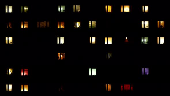 light flickers in the windows of a multistory building.