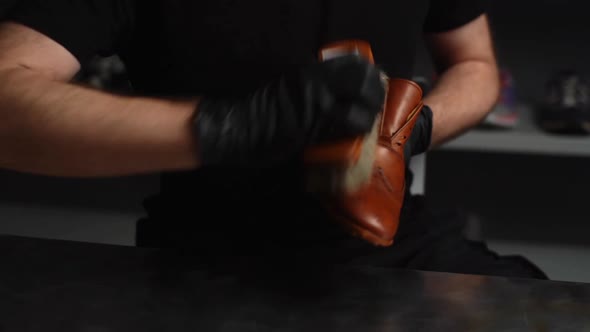 Closeup Hands of Shoemaker Wearing Black Gloves Polishing Light Brown Leather Shoes with Brush