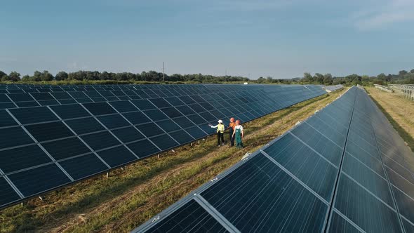 Aerial Shot of Three Solar Energy Engineers on a Large Solar Farm