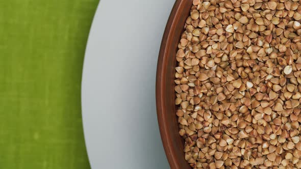 Rotating Bowl with Buckwheat on White Plate on Green Table Cloth