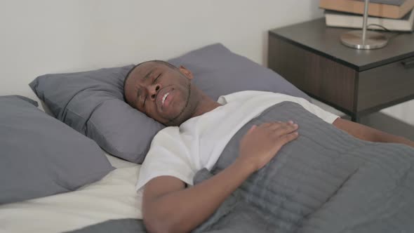 African Man Waking Up From Nightmare in Bed
