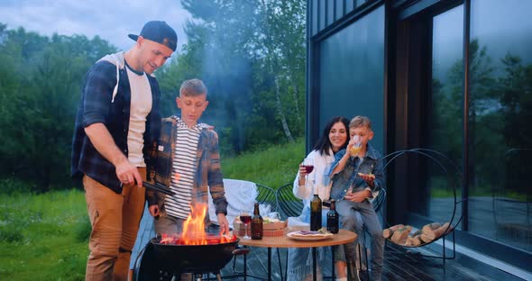 Happy Parents and Children Cooking BBQ Party Outdoors Near Own House