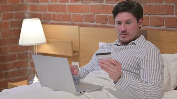 Middle Aged Man with Unsuccessful Online Payment on Laptop in Bed