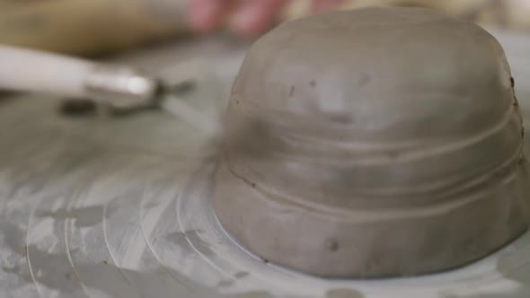 Close up view of female potter using loop tool for finishing pottery at pottery studio