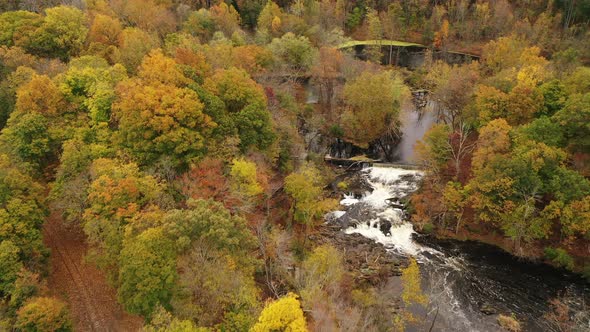 An aerial shot of the fall foliage in upstate NY. The camera dolly in then tilt down over trees, a r