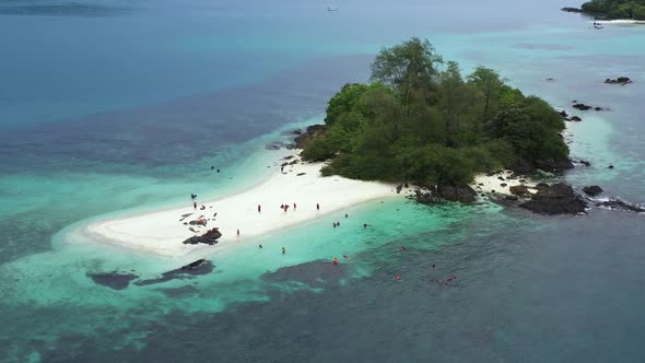 People on a tropical small island in the middle of the ocean. Aerial view drone shot
