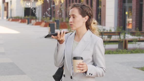 Businesswoman Recording Voice Message on Smartphone Outdoors