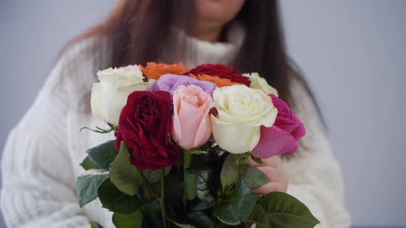 Woman Holding Rose Bouquet and Touching Green Leaves