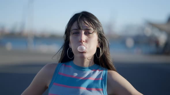 Face of Darkhaired Girl Blowing Bubble with Chewing Gum Outdoors