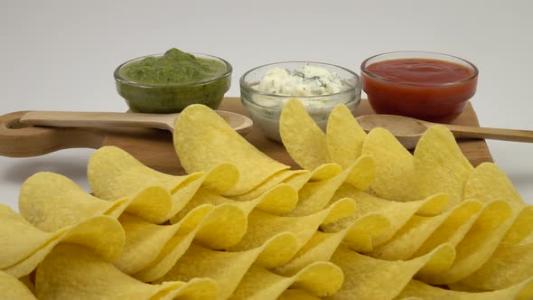 Glass bowls with different sauce stand on the background of potato chips