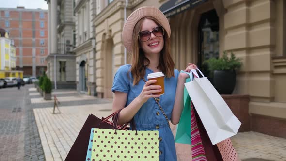 Young Woman with Shopping Bags Walking in a City at Summer Day