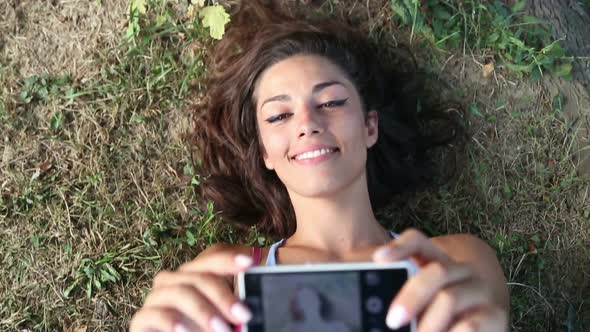 Three young adults taking a selfie lying on the grass