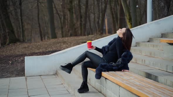 Sexy young woman with a cup of coffee outdoors. 