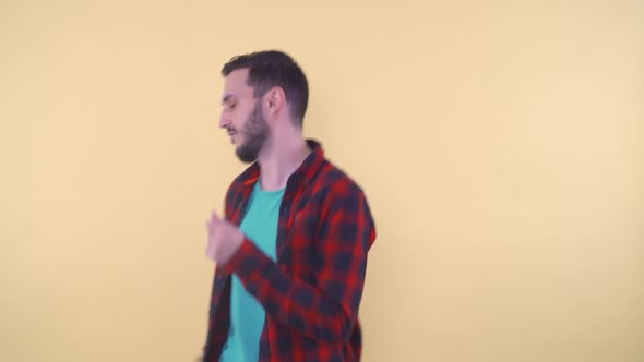 Handsome Young Man Dancing Against a Yellow Background in Studio