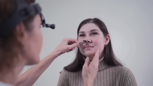 Female ENT Doctor Examines Patient's Sinuses with Medical Instrument in Modern Clinic