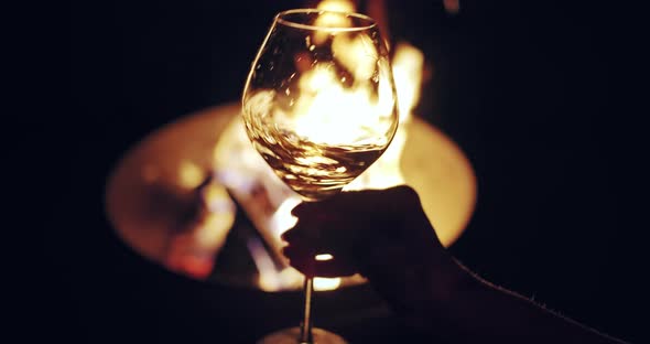 Glass of White Wine Slightly Shaking Against Camp Fire Background