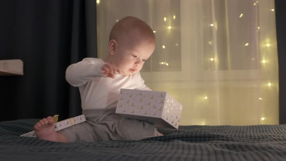 Cute Kid Opening a Gift Box and Taking Out Some Kind of Present From It