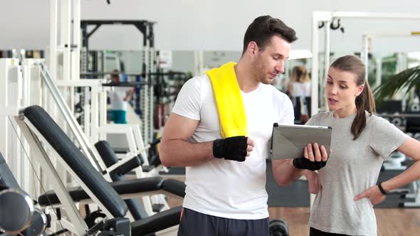 Sporty Man Ad Woman Using Pc Tablet at Gym.