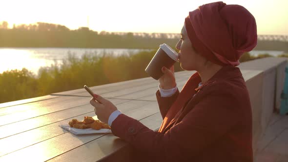 Young Muslim Woman Wearing Hijab Having Coffee Break Outdoor on City Background