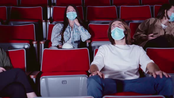 Young people in medical masks laughing at cinema theater