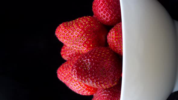 Strawberries without tails lie in white bowl or plate. It rotates