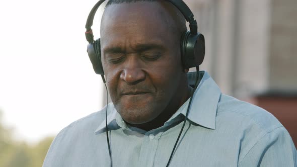 Overjoyed Emotional Senior African American Man Wearing Headphones Have Fun Moving Listening Music