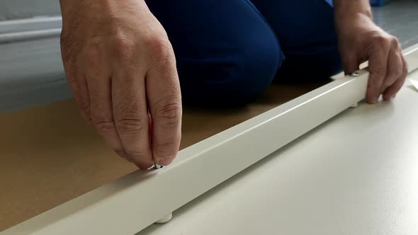 A Man a Handyman in a Blue Jumpsuit is Assembling a Table in Closeup