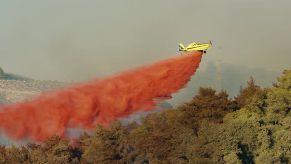 Fire fighter plane drops fire retardant on a forest fire in the hills