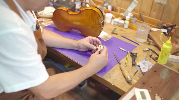 Anonymous luthier with violin bridge in workshop