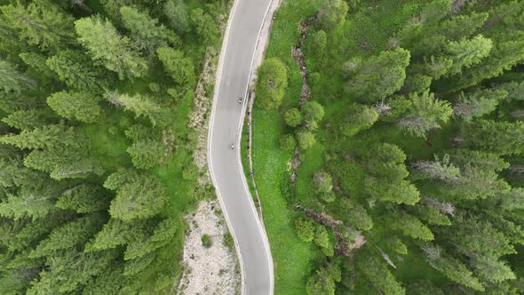 Flying above motorbikers and cyclists riding down a winding mountain road in the Dolomites