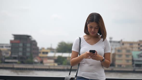 Beautiful young Asian woman using smartphone enjoying reading social media.