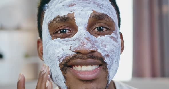 African American which Poses Into Camera while Applying Face Mask