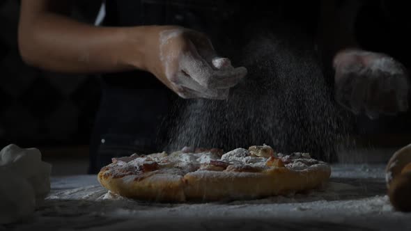 Slow motion of woman hands sifting flour on pizza