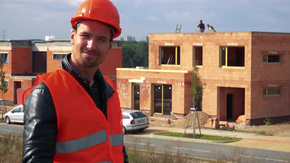 A Young Construction Worker Smiles and Motions the Camera in a Gesture of Invitation