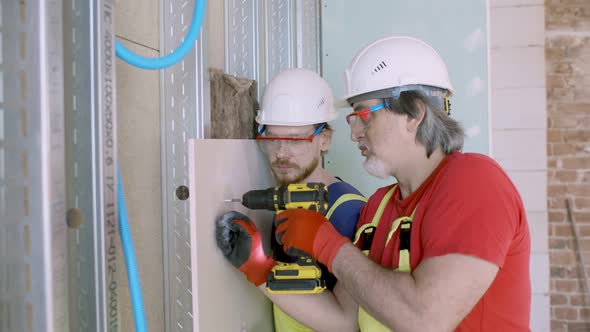 Construction Workers Build Wall Using Screwdriver Indoors