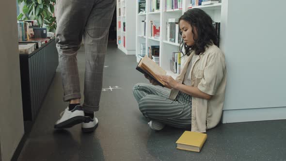 Young Asian Woman Reading Book in Library