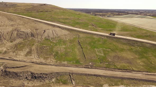 Industrial dump truck transporting soil up to landfill, aerial drone view