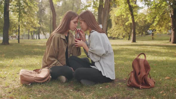 Twin Sisters Enjoying Drink in Park